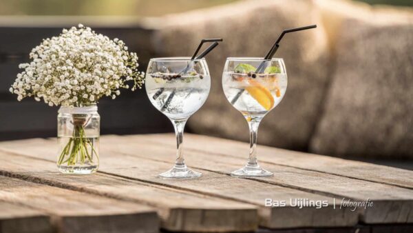 Twee gin tonic op een tafel met een bos bloemen (foto: Bas Uijlings Fotografie)