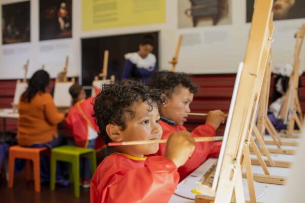 Kinderen met rode schorten die aan het schilderen zijn bij het Mauritshuis Den Haag
