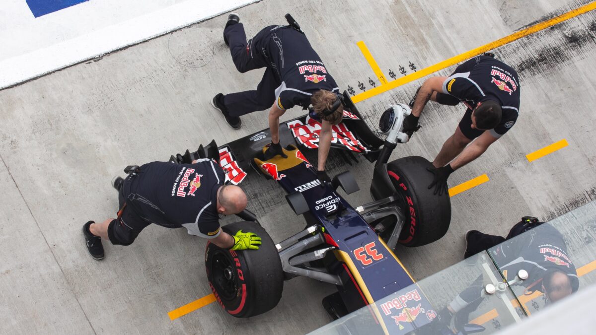 Technische staf bij Formule 1 die de racewagen van Max Verstappen in de paddock duwen
