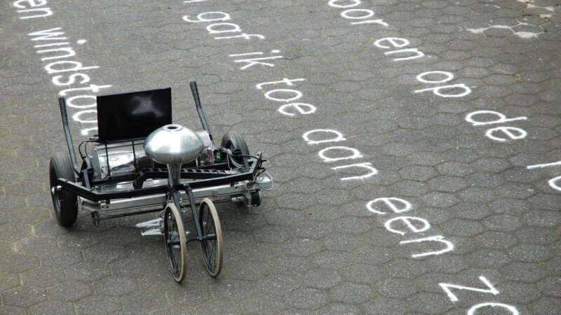 Gijs van Bon machine die met zand een tekst schrijft op de straat