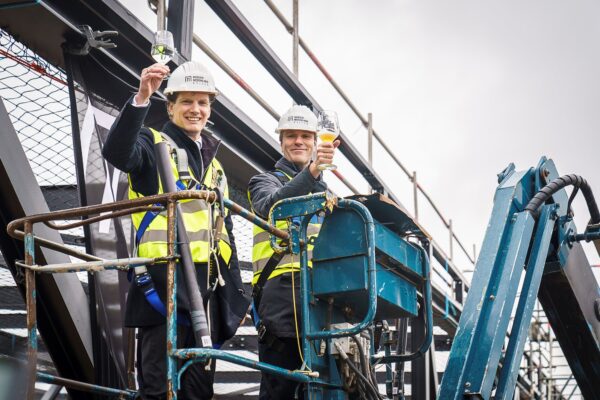 Jacco van der Tak (burgemeester gemeente Barneveld) en Timo Kruft (eigenaar Midden Nederland Hallen) brengen een toost uit op het bereiken van het hoogste punt van de nieuwe theaterhal